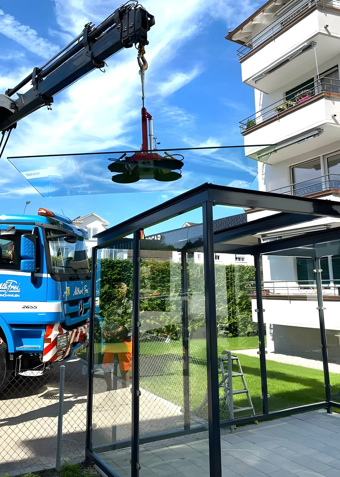 Kran setzt mit einem Vakuumheber eine Glasscheibe auf einen Pavillon aus Stahl und Glas