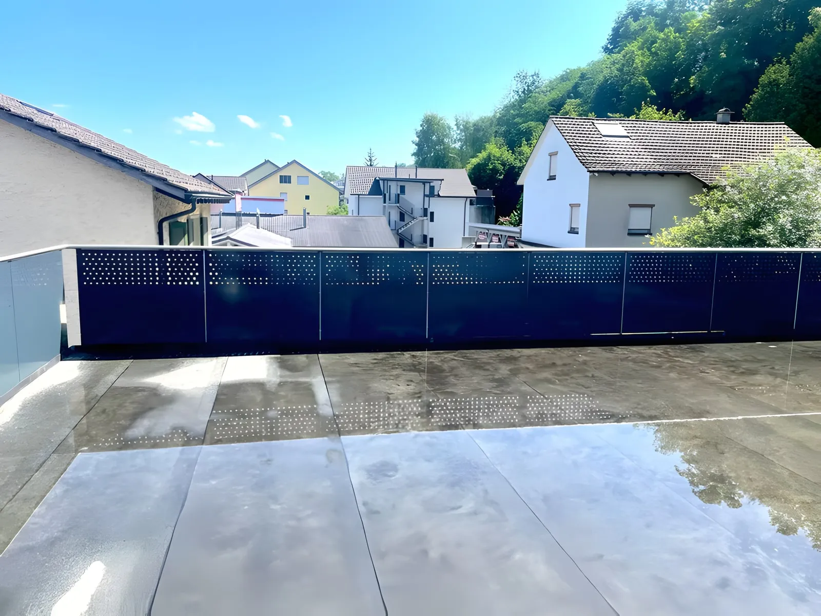 Terrasse mit dunklem Lochblechgeländer und Blick über ein Wohnquartier