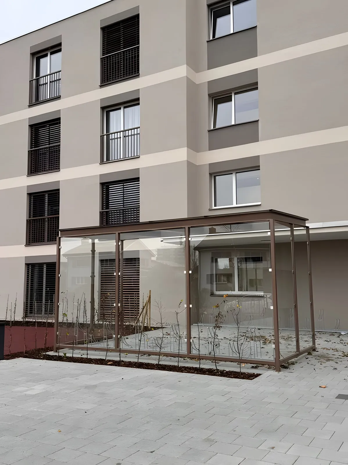 Unterstand aus Metall und Glas vor einem Mehrfamilienhaus