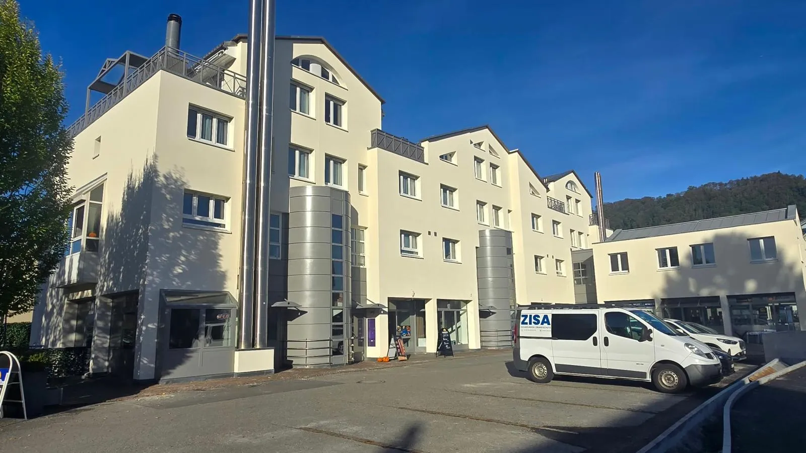 Wohn- und Geschäftshaus mit heller Fassade, neuen Fenstern und runden Treppenhaustürmen aus Metall
